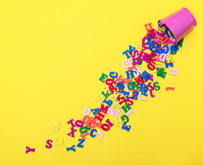Bright yellow background with a pink cup in the top right corner that has letters falling out of it.